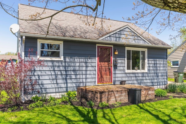 view of front of home featuring roof with shingles and a front yard
