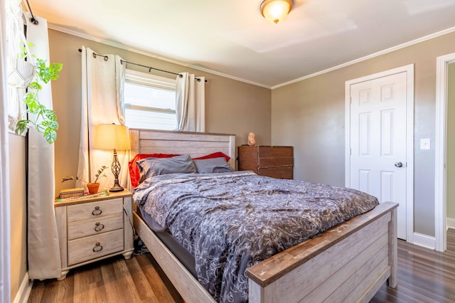 bedroom with dark wood-type flooring, ornamental molding, and baseboards