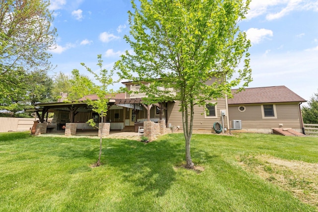 rear view of house with roof with shingles, cooling unit, fence, a yard, and a patio
