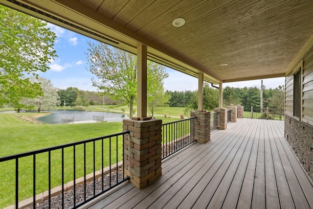 wooden terrace with a lawn, covered porch, and a water view