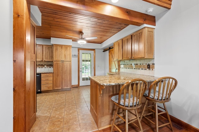 kitchen with a peninsula, a kitchen breakfast bar, wooden ceiling, a ceiling fan, and backsplash
