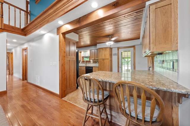 kitchen with a peninsula, black dishwasher, a breakfast bar, and tasteful backsplash