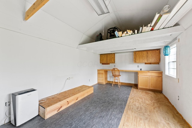 unfurnished office featuring built in desk and vaulted ceiling