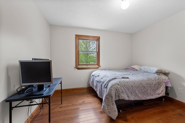 bedroom with baseboards and hardwood / wood-style flooring