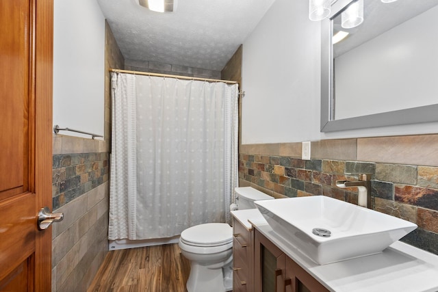 bathroom featuring vanity, wood finished floors, toilet, tile walls, and a shower with shower curtain