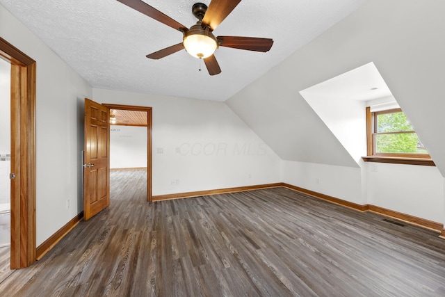 additional living space featuring baseboards, visible vents, dark wood-style floors, and ceiling fan