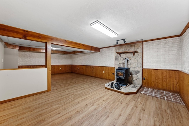 finished below grade area with a wood stove, wood finished floors, wooden walls, and a wainscoted wall