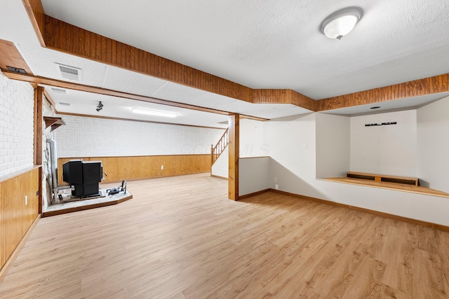 finished below grade area with baseboards, wood walls, and wood finished floors