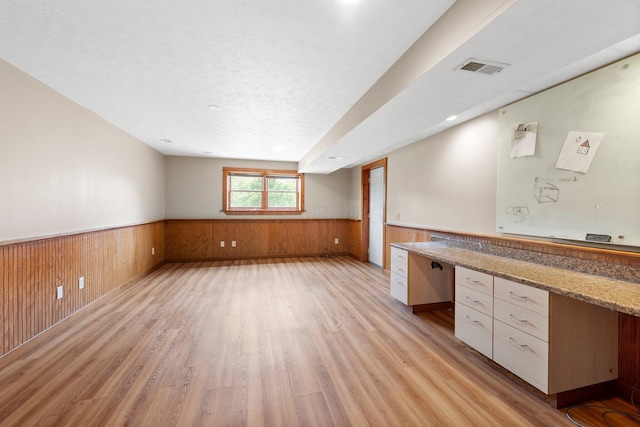 interior space featuring wood walls, wood finished floors, visible vents, and a wainscoted wall