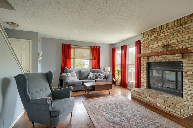 living room with a textured ceiling, baseboards, a fireplace, and hardwood / wood-style floors