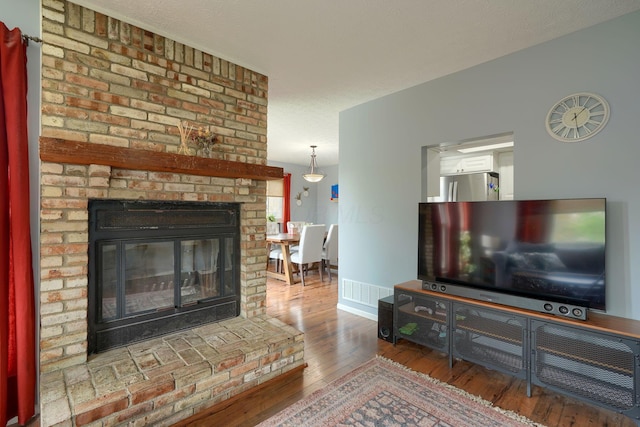 living area featuring baseboards, a fireplace, hardwood / wood-style floors, and visible vents