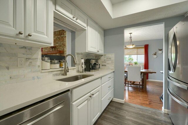 kitchen with backsplash, appliances with stainless steel finishes, a sink, light countertops, and white cabinets