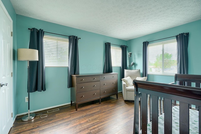 bedroom featuring wood-type flooring, a textured ceiling, visible vents, and baseboards