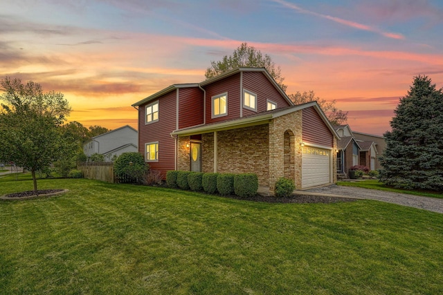 traditional home featuring driveway, brick siding, fence, a yard, and an attached garage