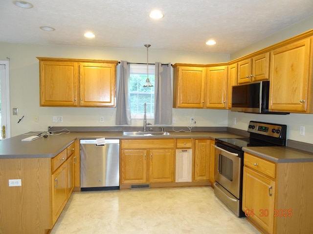 kitchen featuring appliances with stainless steel finishes, hanging light fixtures, a sink, a peninsula, and recessed lighting