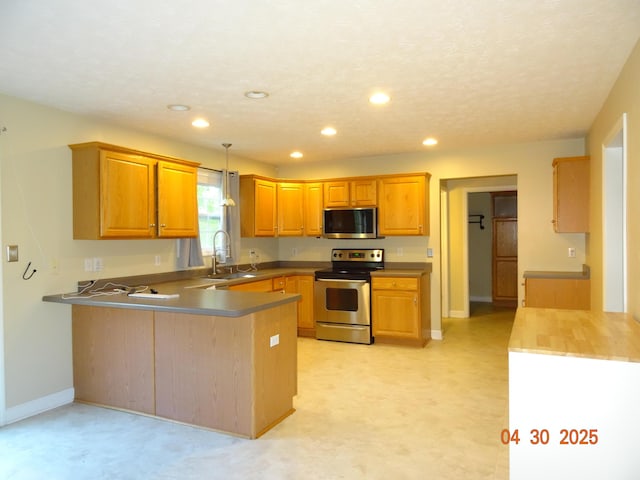 kitchen with a sink, stainless steel appliances, baseboards, recessed lighting, and a peninsula