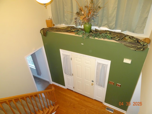 entrance foyer with stairway, a high ceiling, wood finished floors, and visible vents