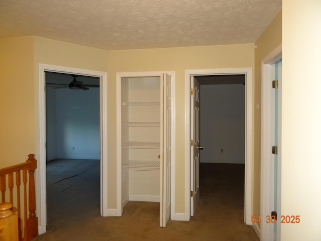 hallway featuring baseboards, a textured ceiling, and carpet
