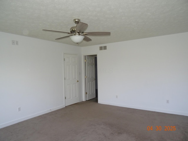 carpeted empty room with visible vents, a ceiling fan, baseboards, and a textured ceiling
