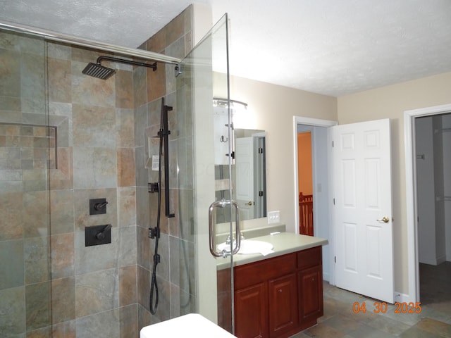 full bathroom featuring vanity, a shower stall, and a textured ceiling