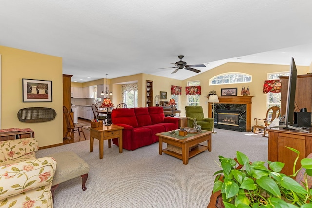 living area with a high end fireplace, carpet, lofted ceiling, and a healthy amount of sunlight