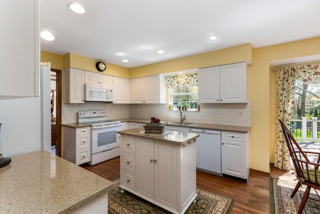 kitchen featuring white appliances, dark wood-style floors, white cabinets, light stone counters, and a sink
