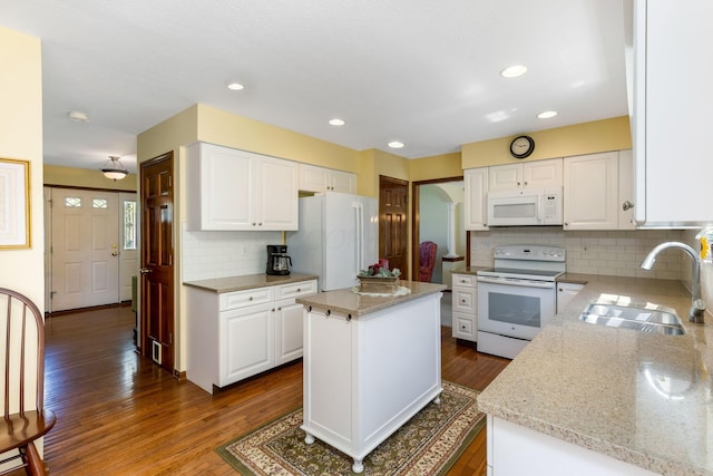 kitchen featuring backsplash, light stone countertops, a sink, white appliances, and dark wood-type flooring