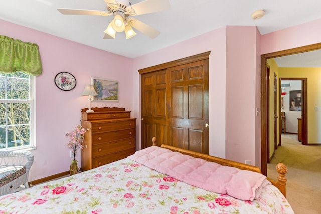 bedroom featuring light colored carpet, baseboards, ceiling fan, and a closet