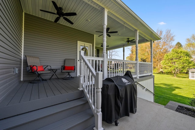 wooden terrace with a ceiling fan, covered porch, and a yard