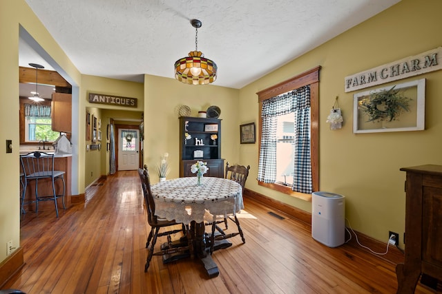 dining area featuring a textured ceiling, baseboards, hardwood / wood-style floors, and visible vents