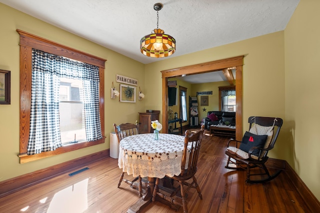dining area featuring baseboards, wood-type flooring, and visible vents
