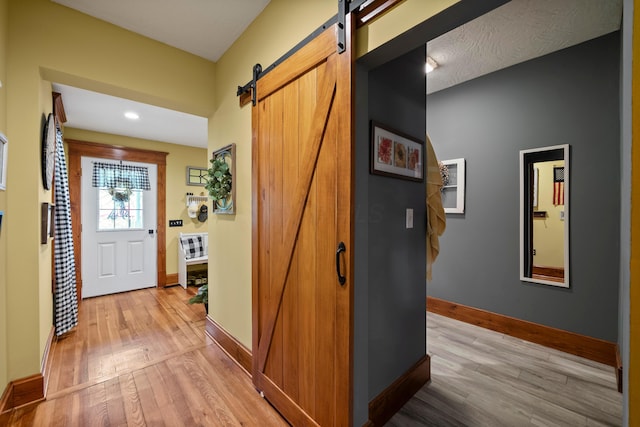 hall featuring recessed lighting, baseboards, light wood finished floors, and a barn door