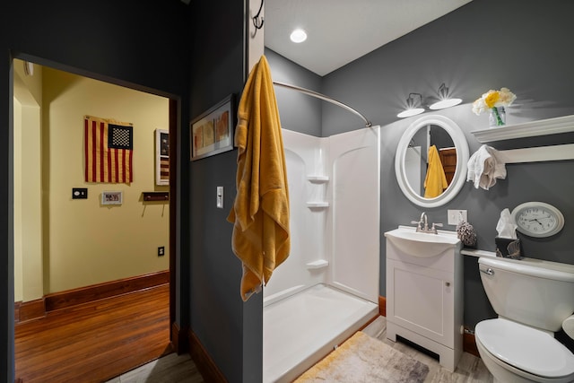 full bathroom with a stall shower, wood finished floors, vanity, baseboards, and toilet