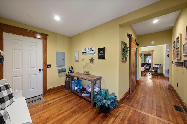 interior space featuring hardwood / wood-style floors, baseboards, a barn door, and visible vents