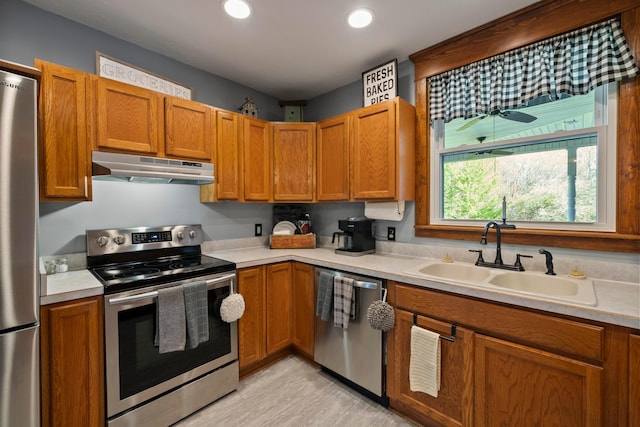 kitchen featuring a sink, appliances with stainless steel finishes, under cabinet range hood, and light countertops