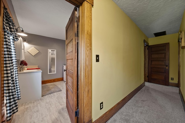 hall with baseboards, carpet, and a textured ceiling