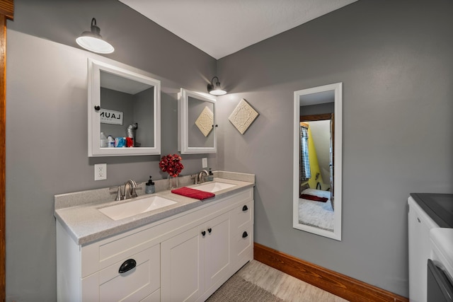 bathroom with double vanity, baseboards, and a sink