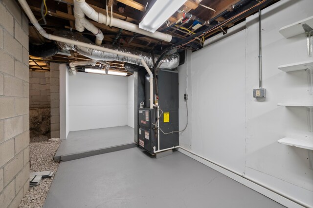unfinished below grade area with heating unit and concrete block wall