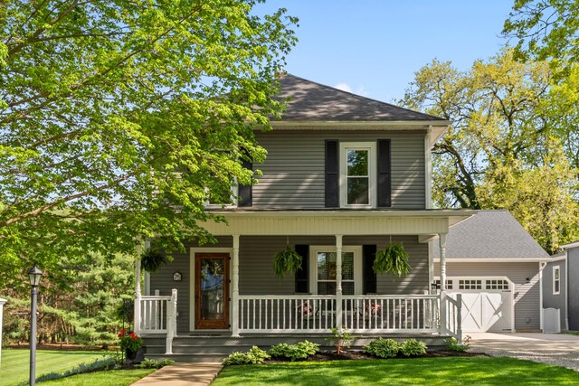 view of front of property featuring covered porch, an attached garage, concrete driveway, and a front lawn