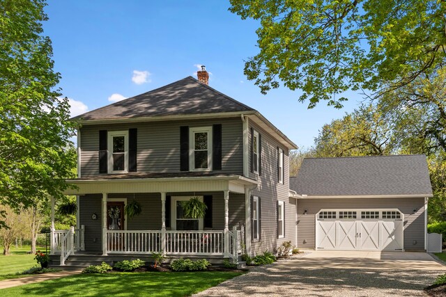 view of front facade featuring a front lawn, a garage, a porch, a chimney, and driveway