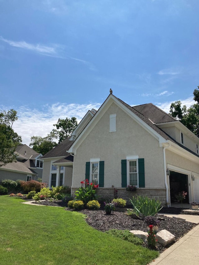 view of side of home featuring stucco siding, a yard, and stone siding