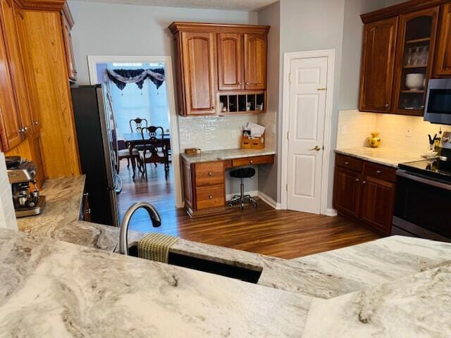 kitchen with dark wood-type flooring, appliances with stainless steel finishes, backsplash, and glass insert cabinets