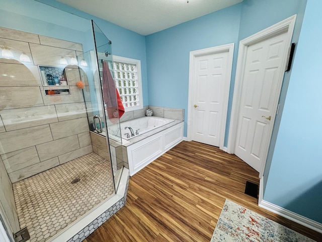 full bathroom with baseboards, a shower stall, wood finished floors, visible vents, and a bath