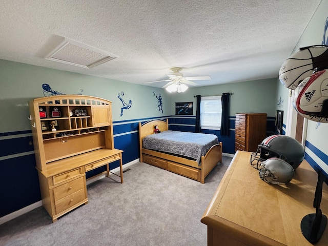 bedroom with ceiling fan, attic access, carpet flooring, and a textured ceiling