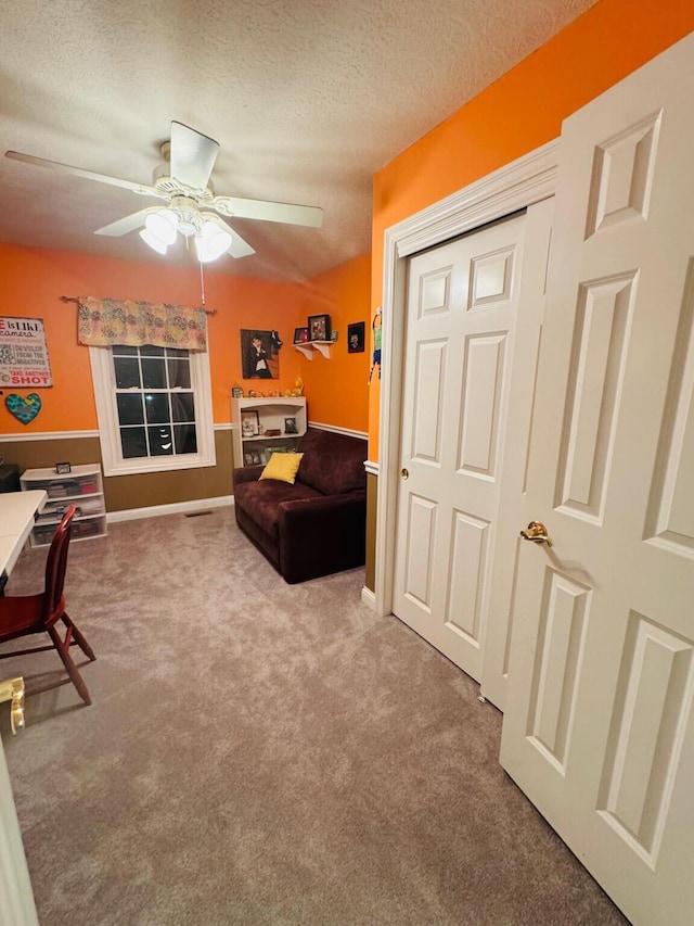 interior space featuring carpet floors, a ceiling fan, and a textured ceiling