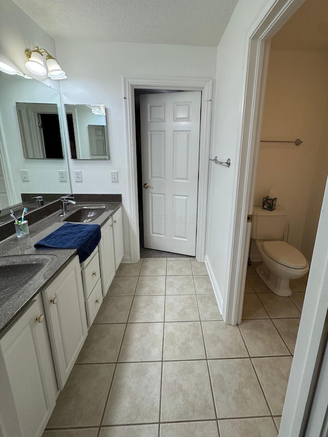 bathroom featuring a sink, tile patterned flooring, toilet, and a textured ceiling