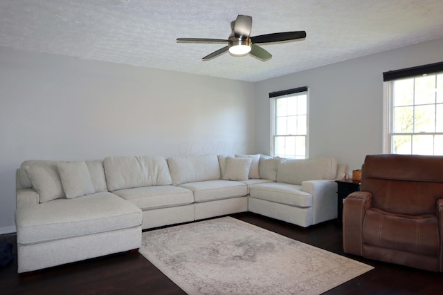 living area with a ceiling fan, dark wood-style flooring, and a textured ceiling