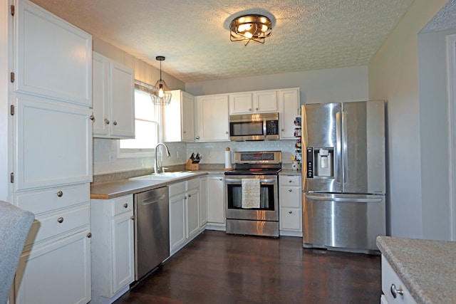 kitchen featuring white cabinetry, a textured ceiling, appliances with stainless steel finishes, and a sink