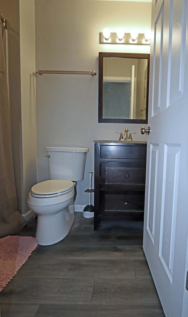 bathroom featuring vanity, curtained shower, toilet, and wood finished floors