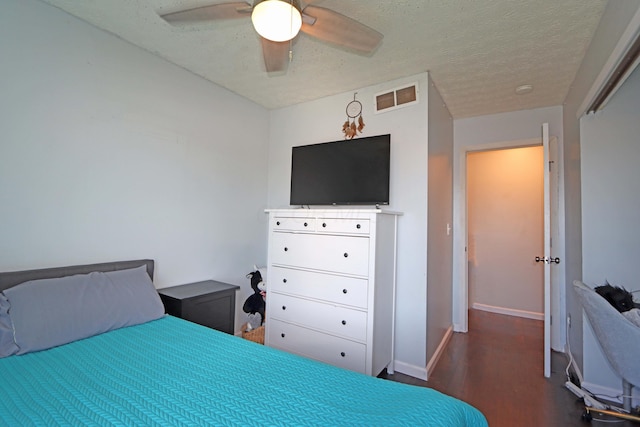 bedroom with ceiling fan, a textured ceiling, baseboards, wood finished floors, and visible vents